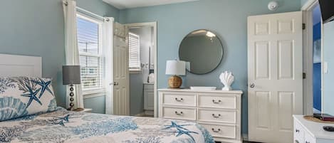 A bedroom with a bed, a dresser, a mirror, and a door.
