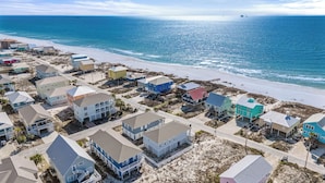 A coastal residential area with houses along the beach, featuring a mix of single and multi-story buildings, some with balconies. - Bikini Bottom by Southern Vacation Rentals (Gulf Shores)