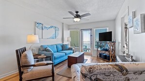 A living room with a blue sofa, a wooden chair, a coffee table, and a television on a stand.