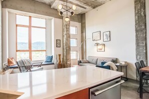 A modern kitchen with a large island, a dining area with a table and chairs, and a seating area with a sofa and chairs.