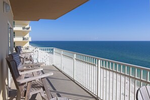 A balcony with wooden chairs and a table, overlooking a beach and the ocean. - Crystal Shores West #501 by Southern Vacation Rentals (Gulf Shores)