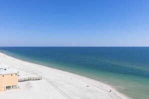 A beach with a wooden walkway leading to a building with a sloped roof. - Crystal Shores West #501 by Southern Vacation Rentals (Gulf Shores)