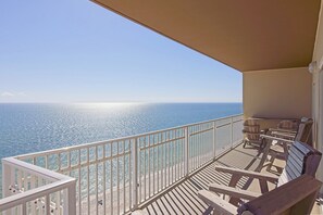 Ein Balkon mit Meerblick, Holzmöbel und einem weißen Geländer.