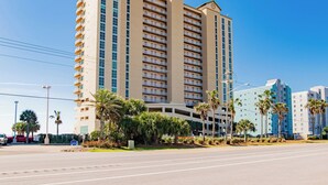 A tall hotel with multiple floors, balconies, and a parking garage.