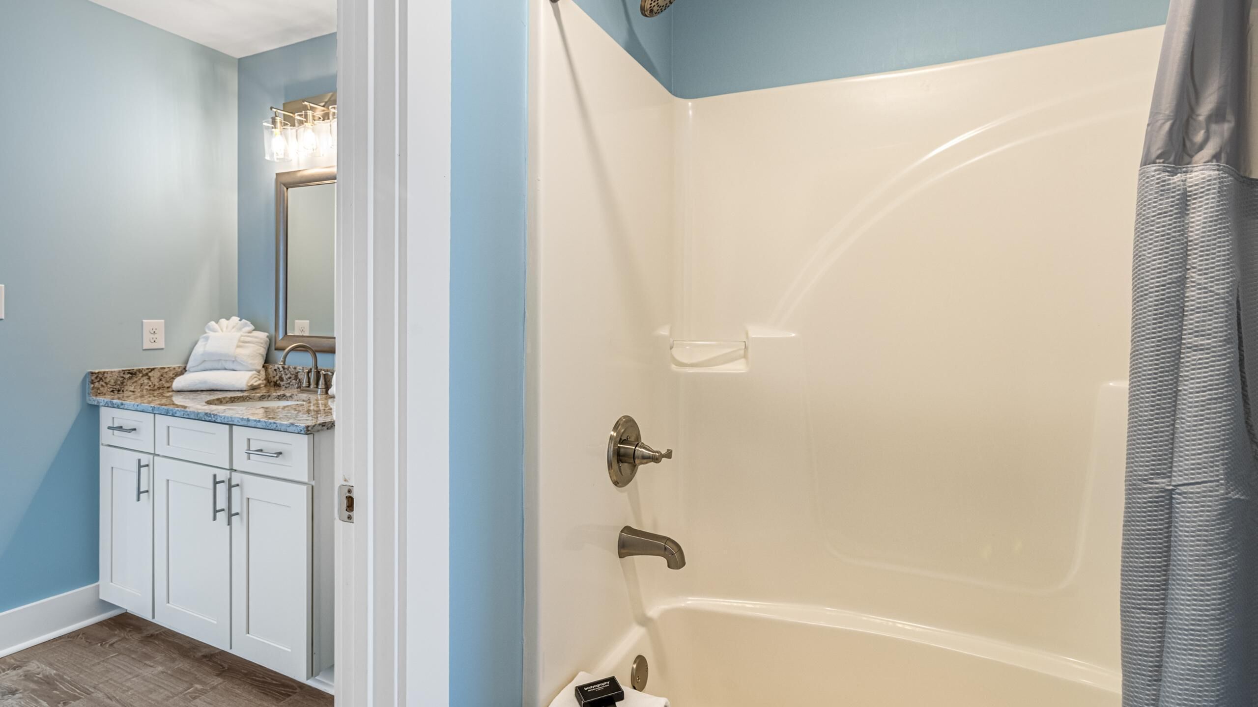 A bathroom with a bathtub, a sink with a mirror, and a towel rack.