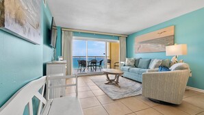Un salon avec vue sur la mer, un balcon avec des chaises et un canapé.