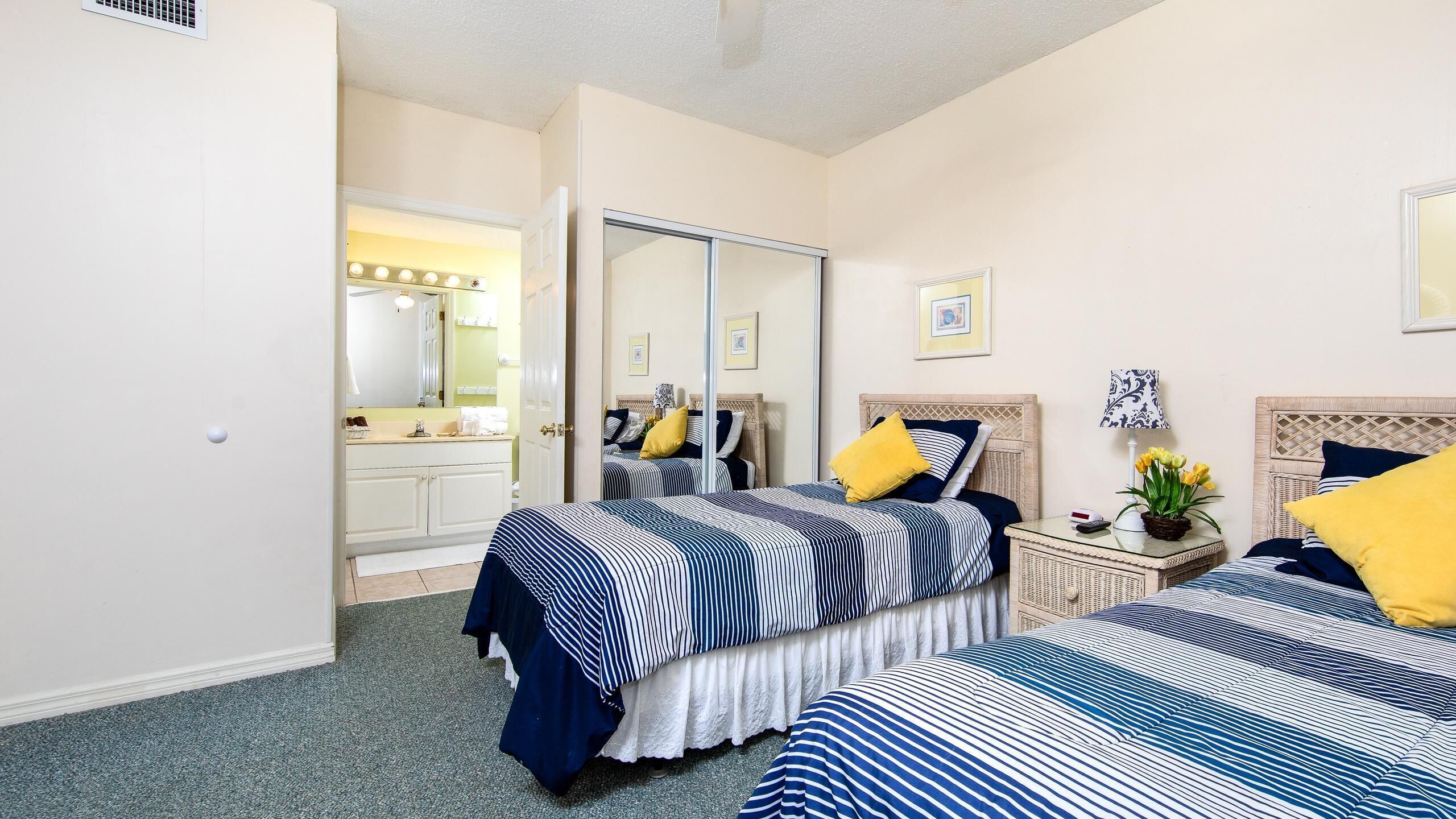 A hotel room with two beds, a vanity with a mirror, and a small table with a lamp.