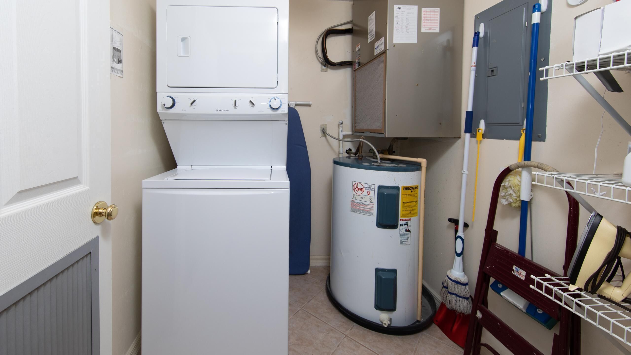 A compact laundry room with a washer and dryer, a water heater, and a mop rack.