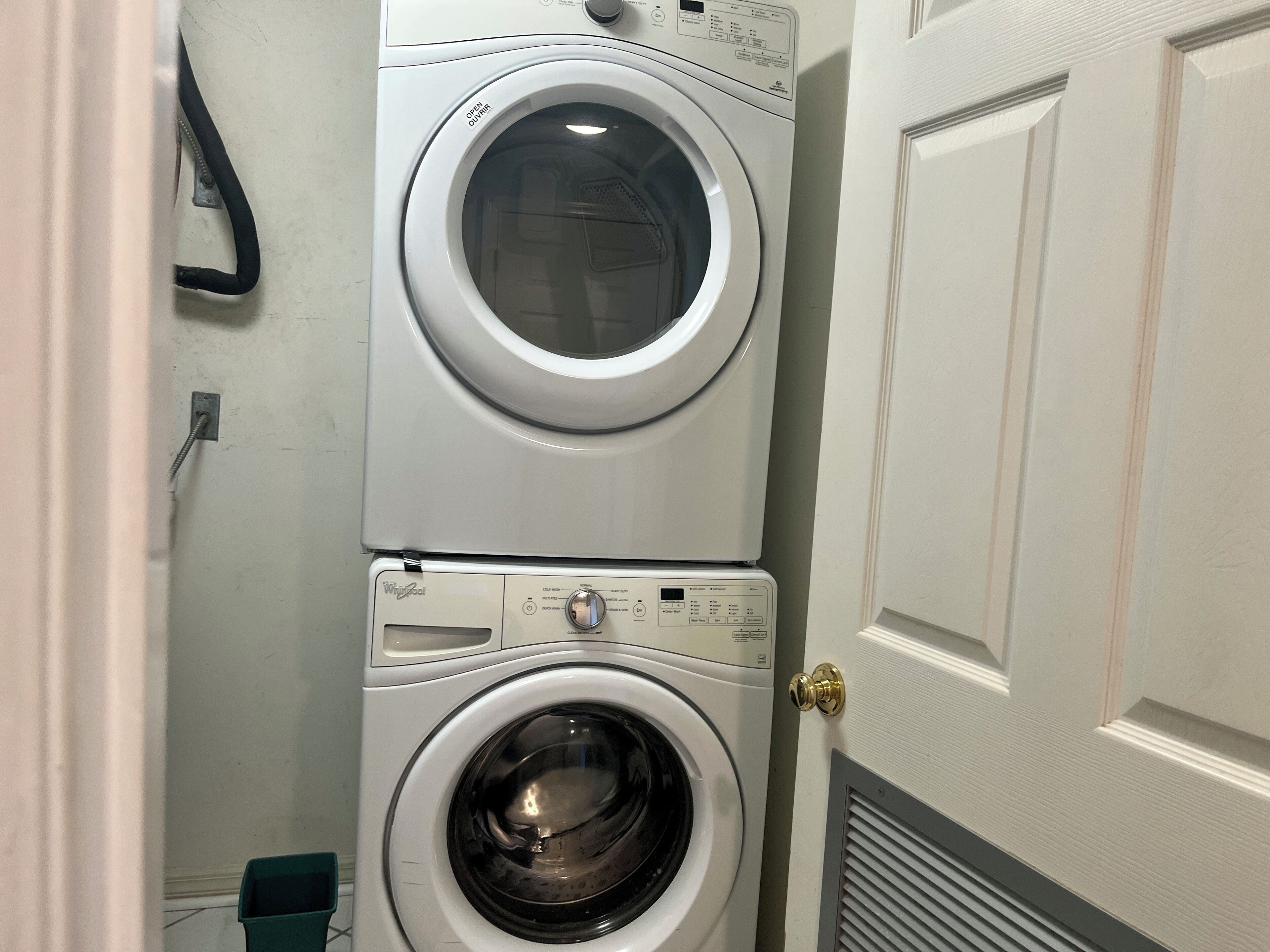 A stacked washer and dryer unit in a laundry room with a door and a vent.