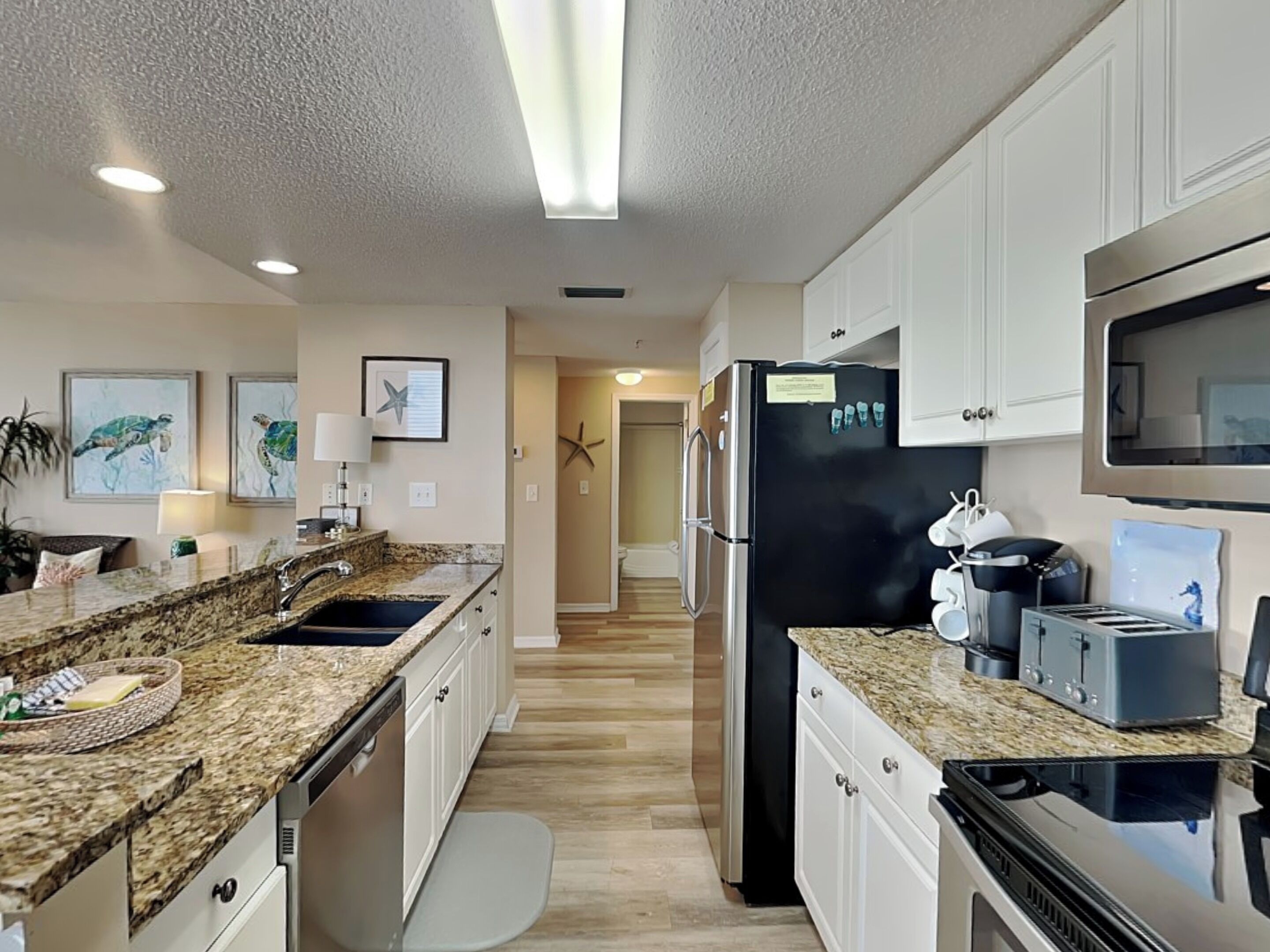 A modern kitchen with granite countertops, stainless steel appliances, and white cabinetry.