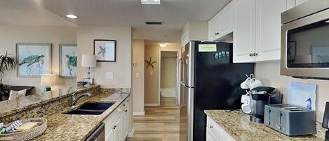 A modern kitchen with granite countertops, stainless steel appliances, and white cabinetry.