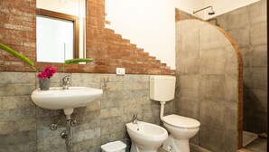 A bathroom with a sink, bidet, toilet, and a shower area.