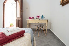 Une chambre à coucher avec un lit, un bureau et une chaise. Il y a une fenêtre donnant sur l’extérieur.