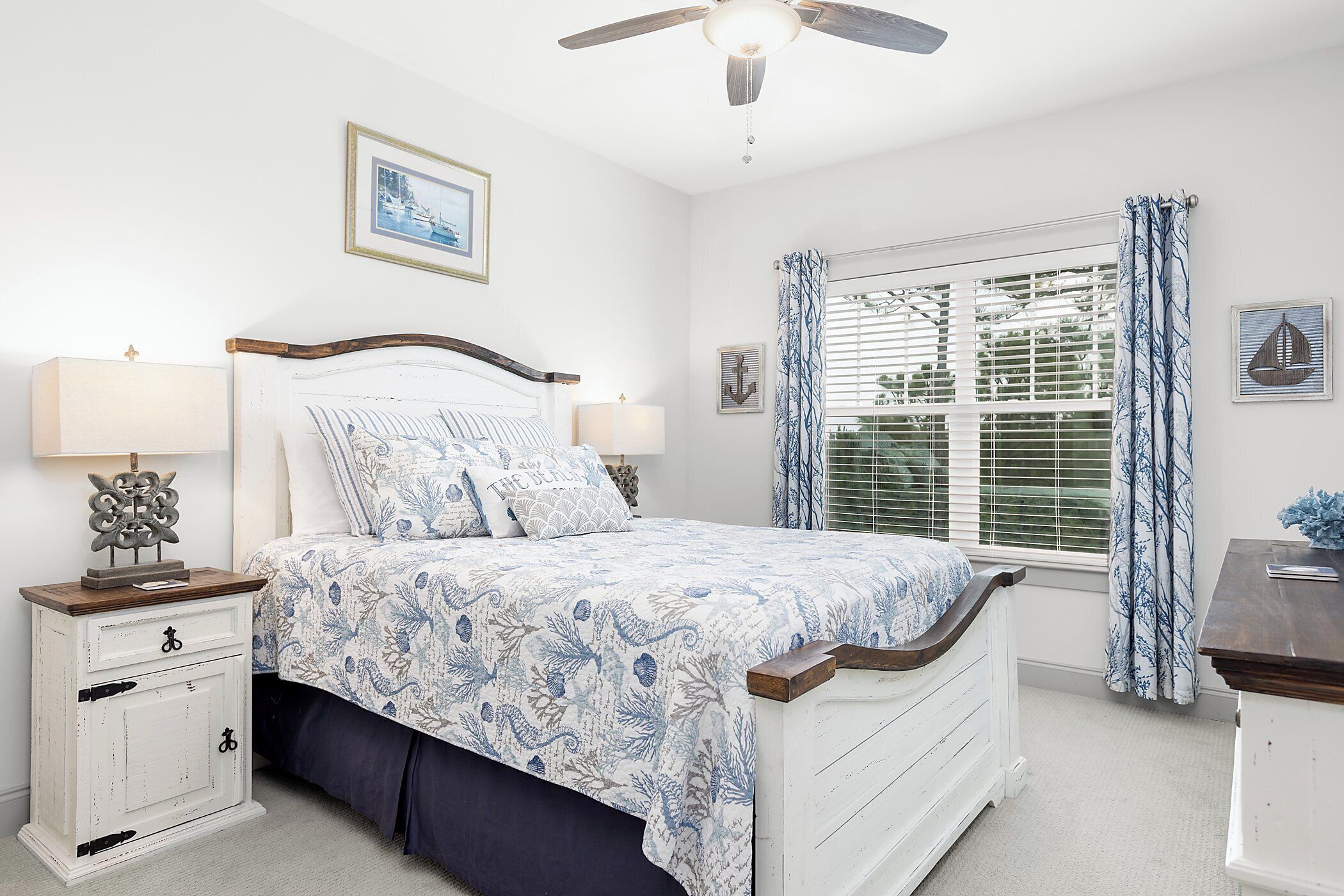 A bedroom with a bed, nightstands, a ceiling fan, and a window with curtains.