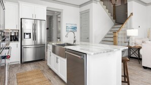 A modern kitchen with white cabinetry, stainless steel appliances, and a marble countertop. - Endless Summer by Southern Vacation Rentals (Orange Beach)