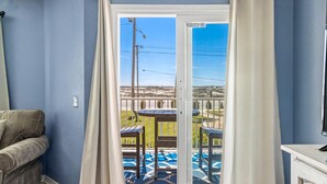 A room with a sliding glass door leading to an outdoor patio with a table and chairs. - Grand Beach Resort by Southern Vacation Rentals (Gulf Shores)