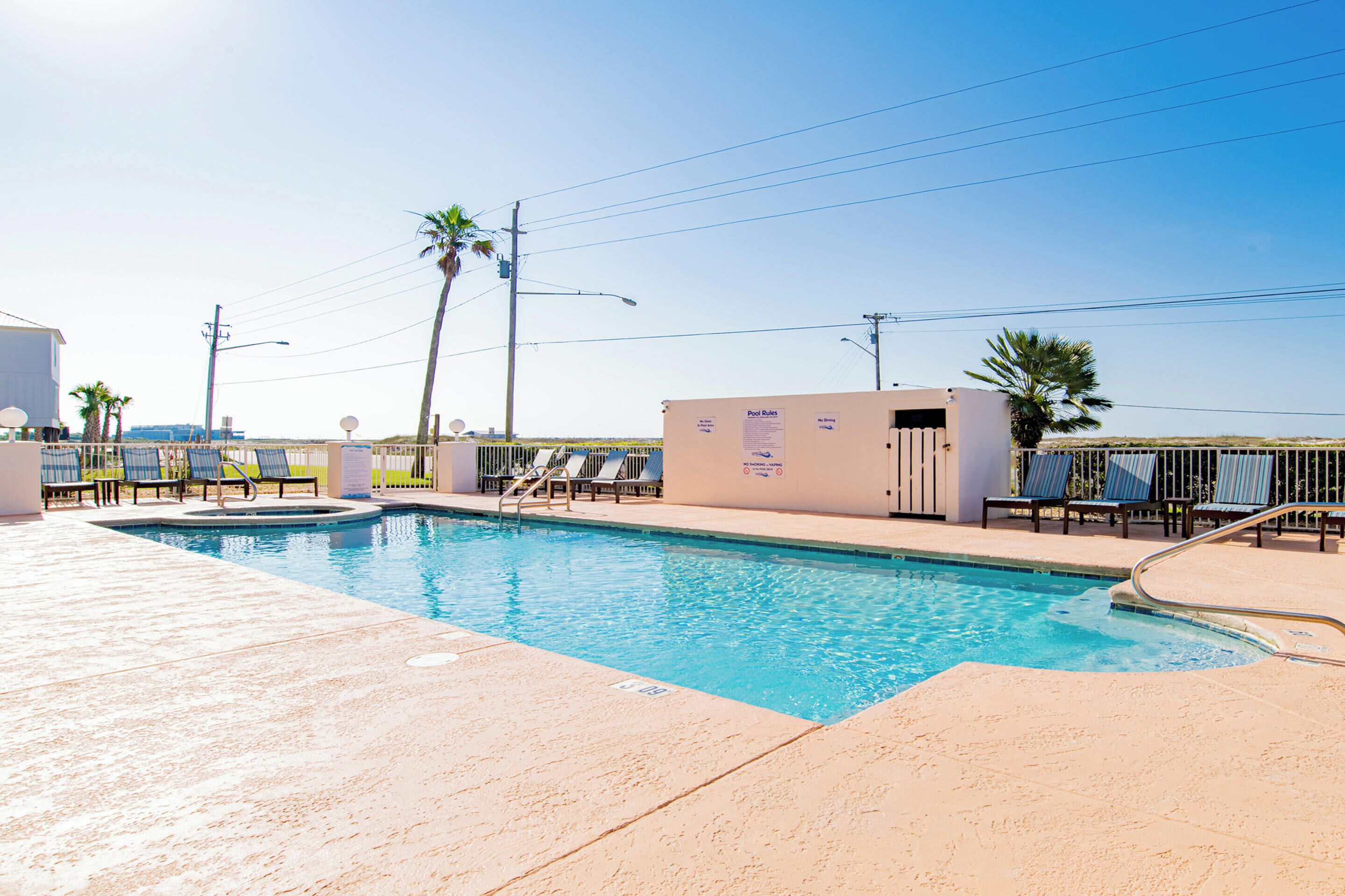 A swimming pool with lounge chairs and a signboard.