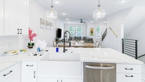 A modern kitchen with white cabinetry, a central island with a sink, and pendant lighting.