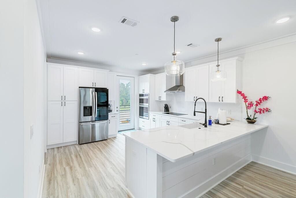 Una cocina moderna con armarios blancos, electrodomésticos de acero inoxidable y una isla central.