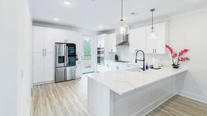 A modern kitchen with white cabinetry, stainless steel appliances, and a central island.