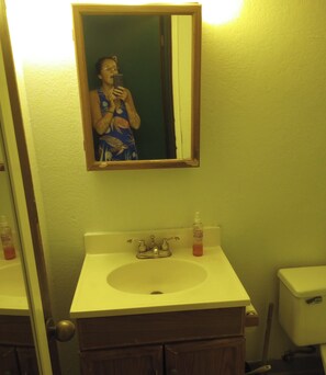 A bathroom with a sink, mirror, and toiletries. - Ocean view Cozy studio condo with gym, AC and kitchenette in  Waikiki (Honolulu)