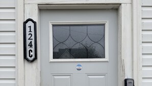 Una puerta blanca con un ventanal, un buzón y un timbre.