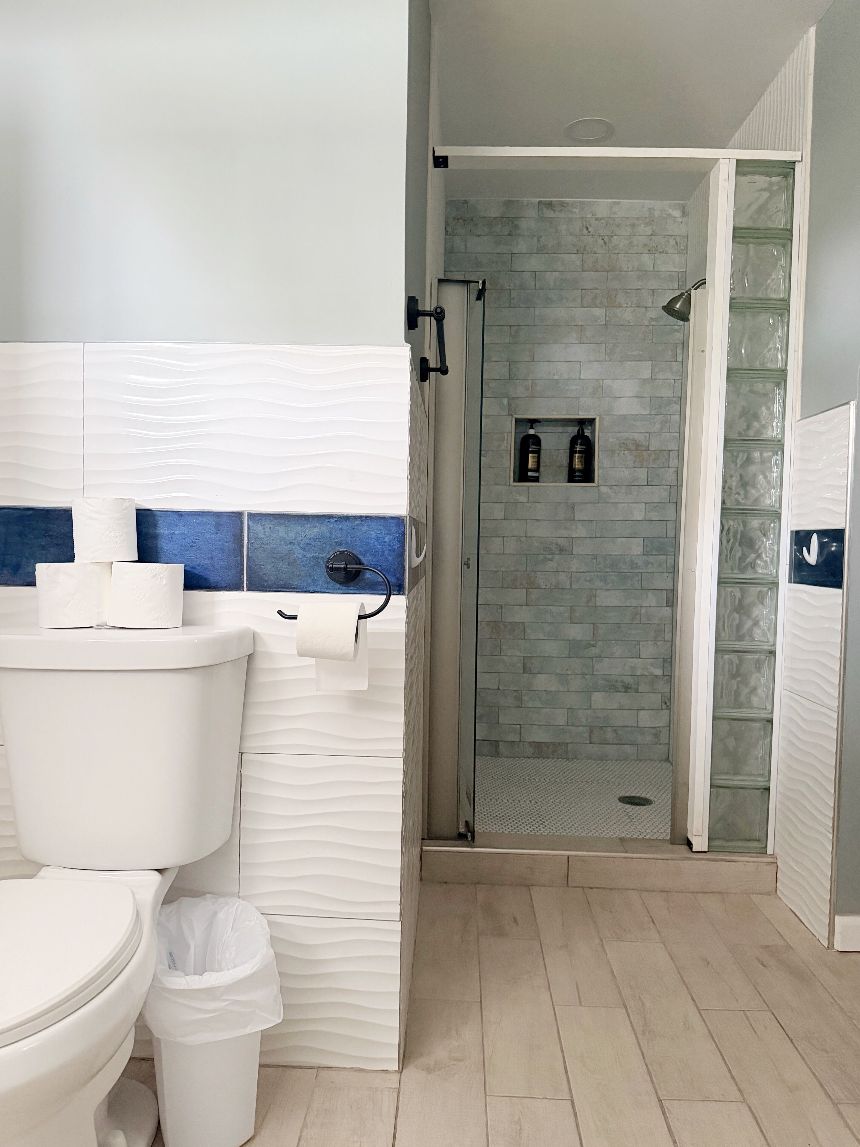Un baño con inodoro, bidé y cabina de ducha con paredes de vidrio.