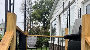 Una terraza de madera con una parrilla y barandilla metálica.