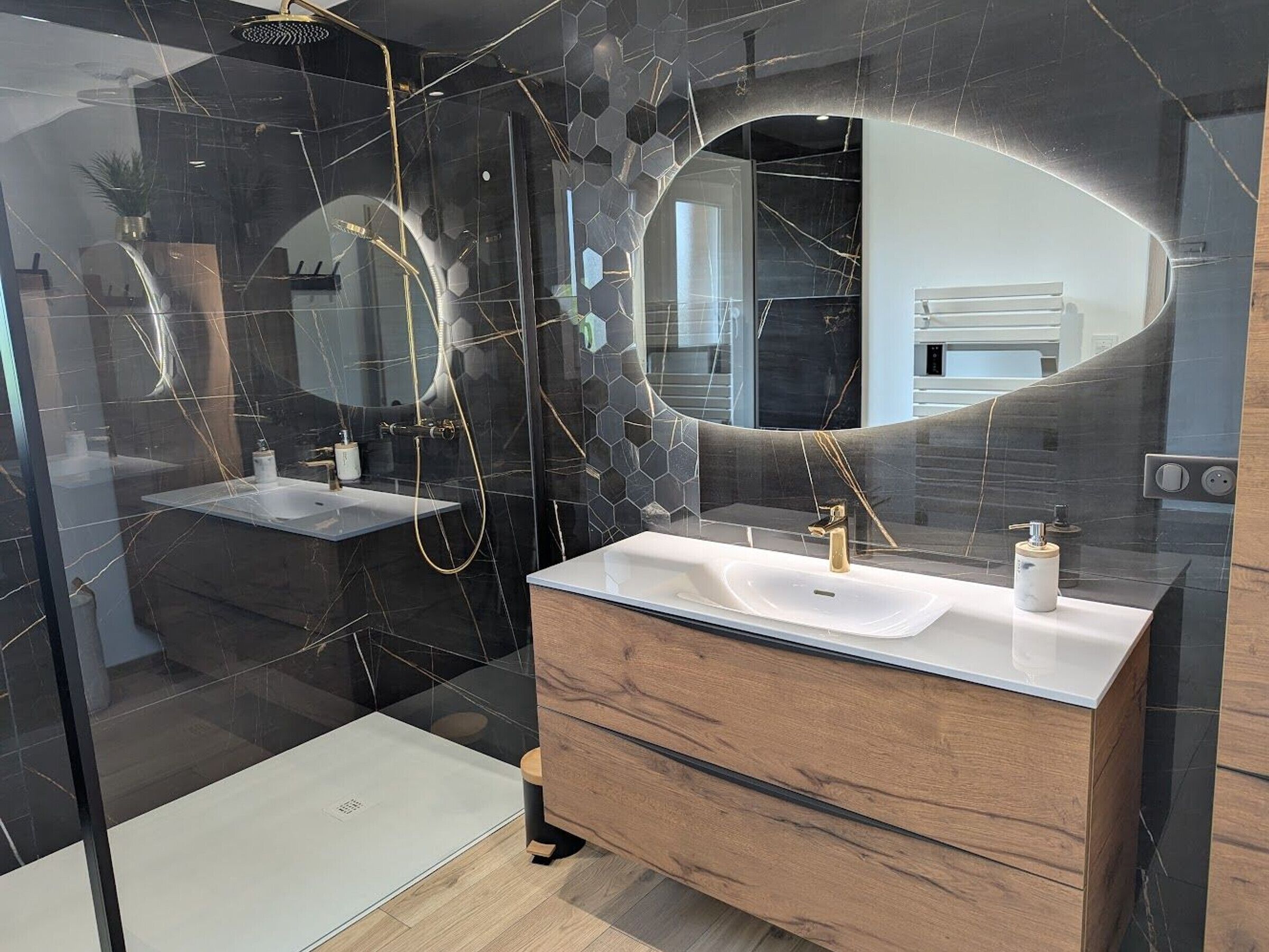 Ein modernes Badezimmer mit einer gläsernen Duschkabine, einem Waschtisch mit großem Spiegel und einer Holzkabine.