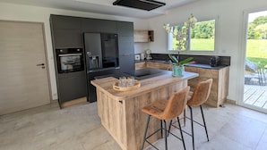 Una cucina moderna con isola centrale, sgabelli da bar e vista sull'esterno.