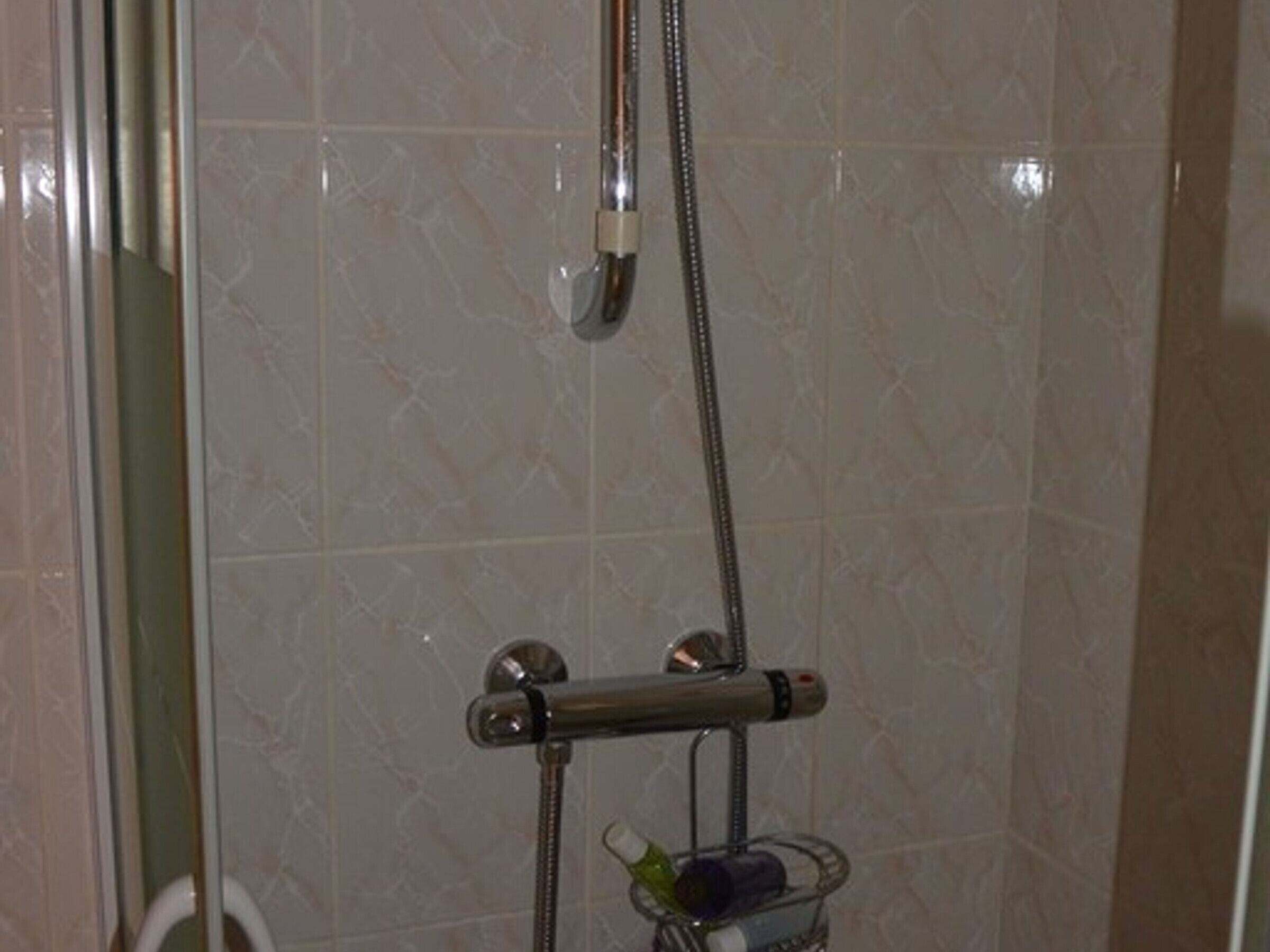 Une douche équipée d’un pommeau de douche à main et d’un robinet fixé au mur.