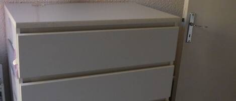 A white cabinet with four drawers against a textured wall.
