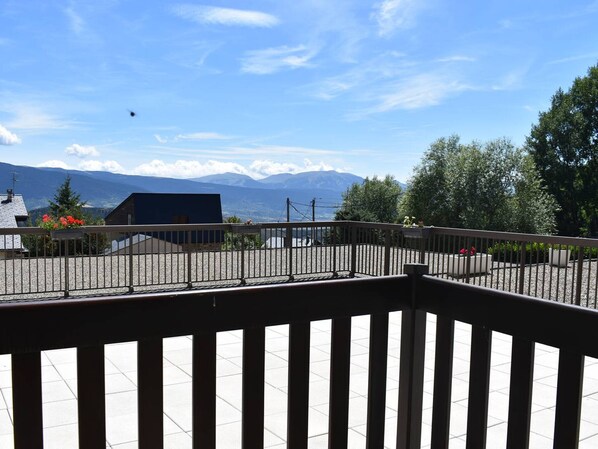 A balcony with a view of mountains and a clear sky.