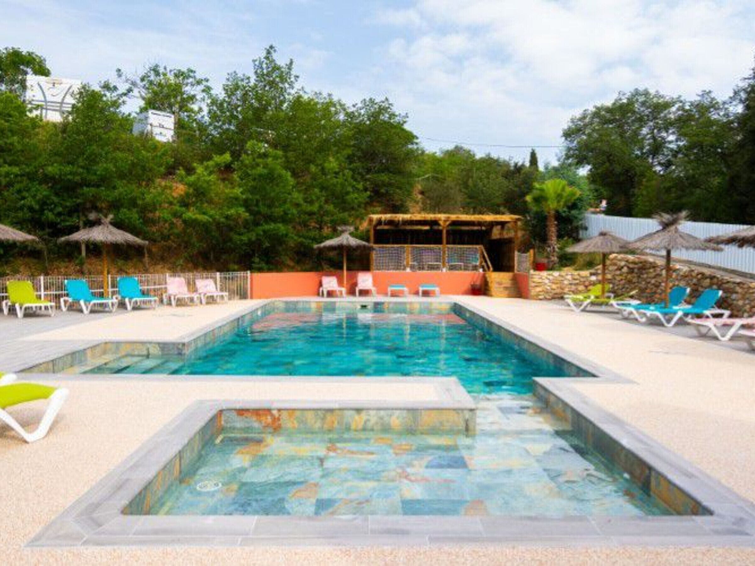 Ein Schwimmbecken mit Liegestühlen und einem schattigen Bereich.