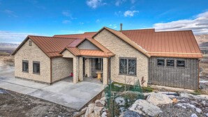 A two-story house with a stone facade, a brown metal roof, and a small front porch.
