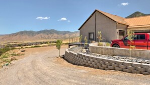 A house with a red truck parked in front, surrounded by a gravel driveway and a stone retaining wall.