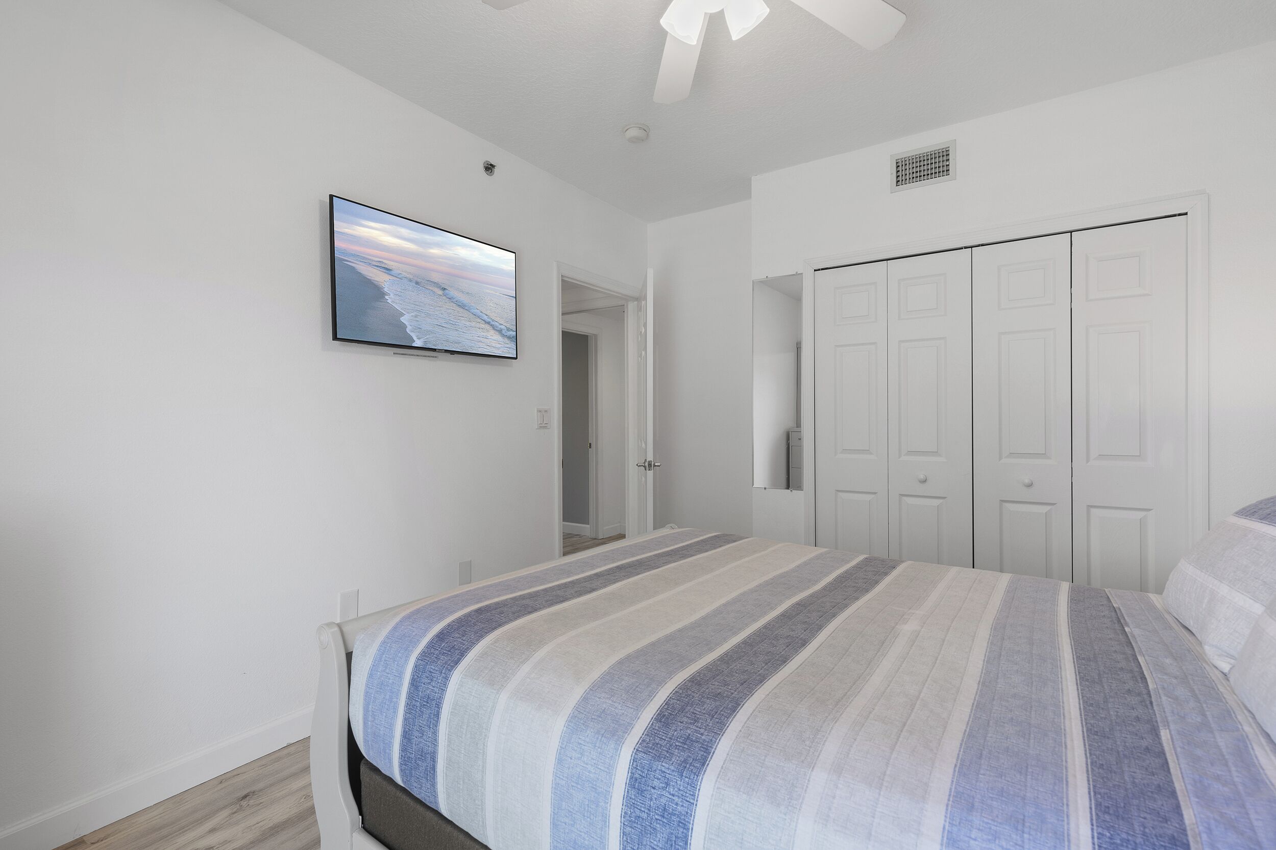 A bedroom with a bed, a television on the wall, and a closet.