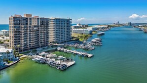 A marina with boats docked, a large hotel building, and a clear blue sky. - Legacy Key #203 by Southern Vacation Rentals (Orange Beach)
