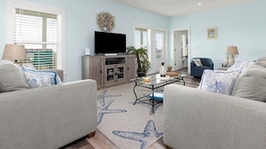 A living room with a flat-screen TV, a coffee table, and two sofas. - Living The Dream by Southern Vacation Rentals (Gulf Shores)