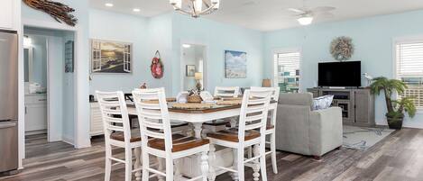 A spacious living room with a dining area, a gray sofa, and a flat-screen TV.