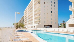 Un área de piscina de hotel con sillas de descanso y una piscina azul cristalina.