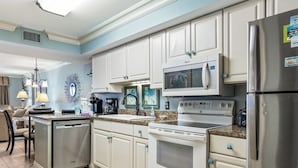 Una cocina moderna con armarios blancos, un refrigerador de acero inoxidable, un microondas integrado y un lavavajillas.