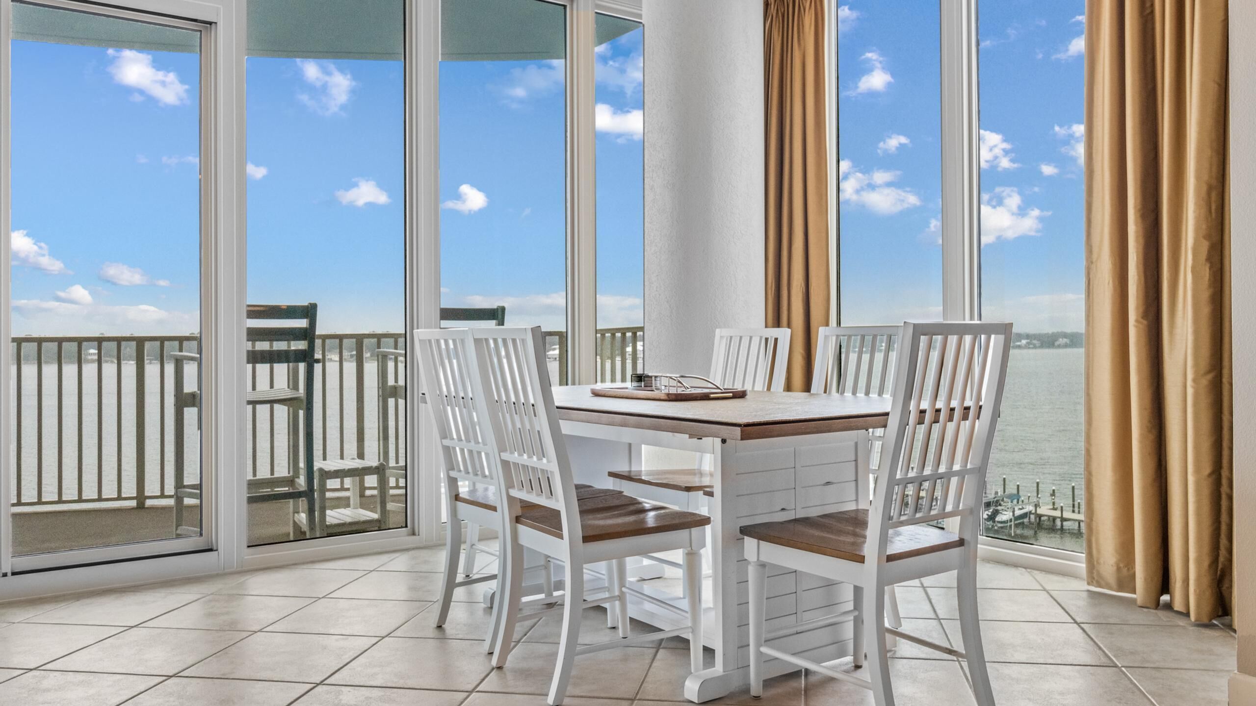 A balcony with a table and chairs, a view of the water, and a railing.