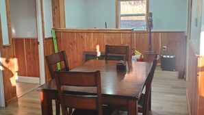 Un coin repas avec une table et des chaises en bois, une fenêtre donnant sur un beau paysage et un ventilateur de plafond.