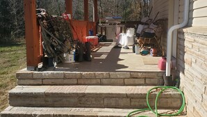 Une véranda couverte avec des marches menant à la maison, un barbecue et du mobilier d’extérieur.
