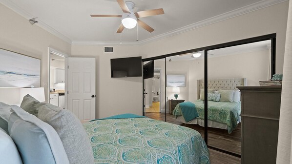 A bedroom with a bed, a ceiling fan, a TV, and a sliding door leading to another room. - Pelican Pointe #1003 by Southern Vacation Rentals (Orange Beach)