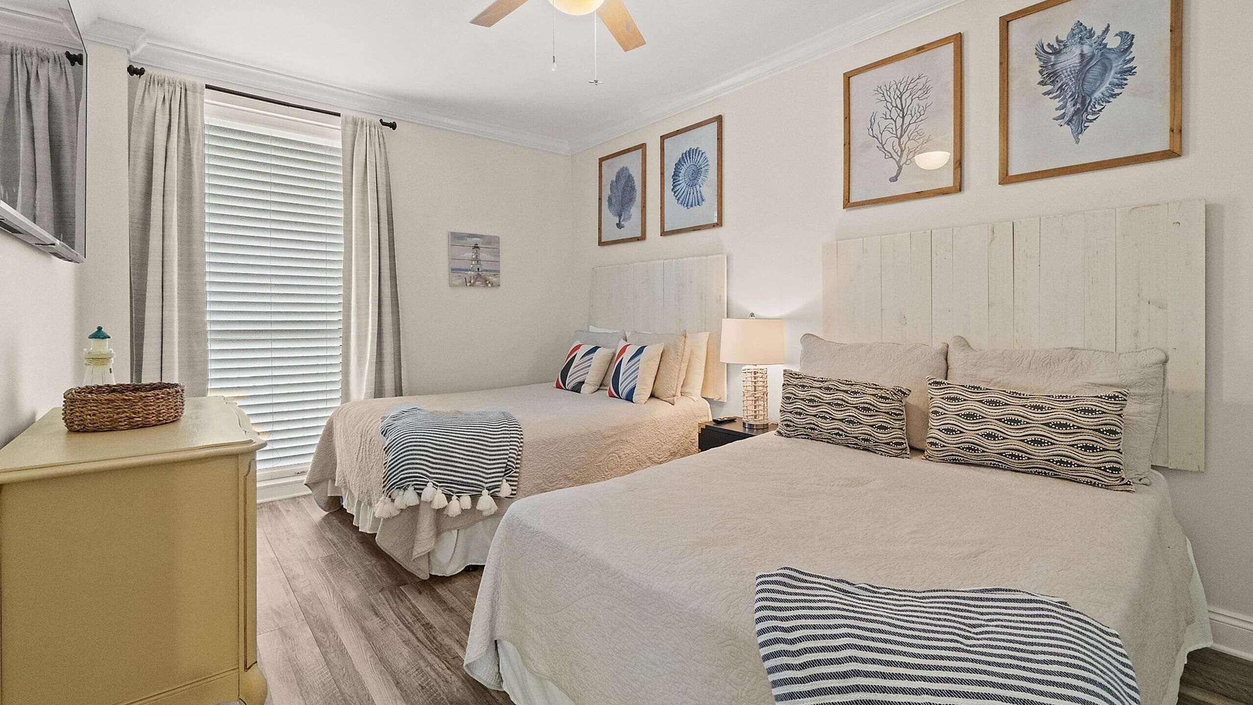 A bedroom with two beds, a wooden headboard, a bedside table, and a lamp.