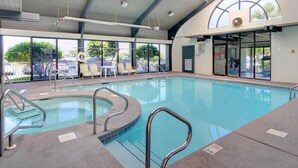 Une piscine intérieure avec des parois en verre transparent, un bord incurvé et un toit ouvrant.