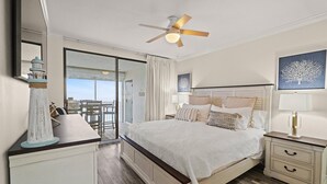 Une chambre d’hôtel avec un lit, des tables de chevet, un ventilateur de plafond et une vue sur l’extérieur.