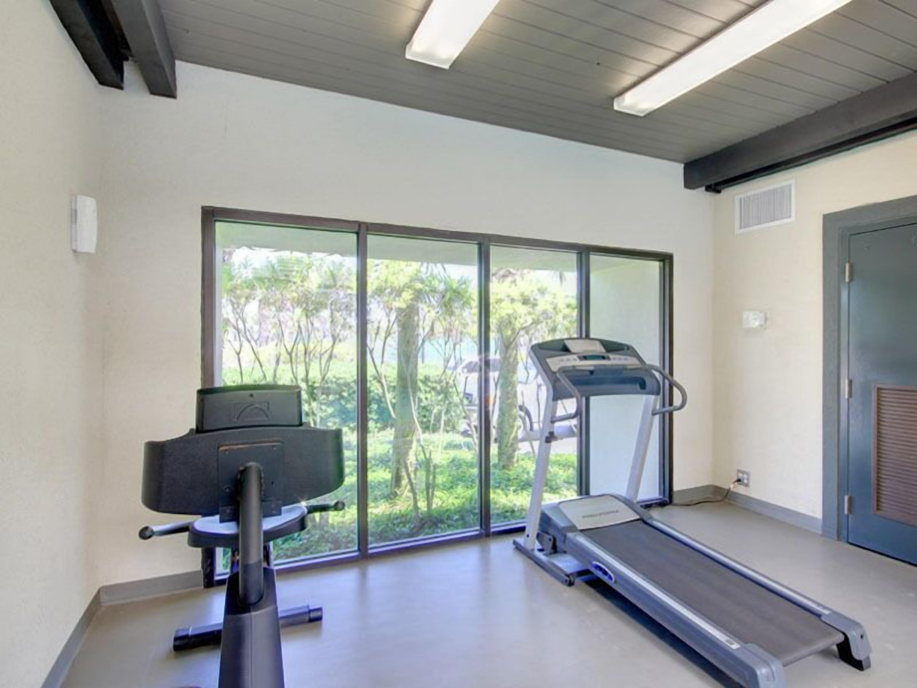 Et moderne fitnesscenter med løbebånd, spinningcykel og vægtbænk.